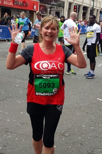A female 'Team QAC' runner completes the 10k run
