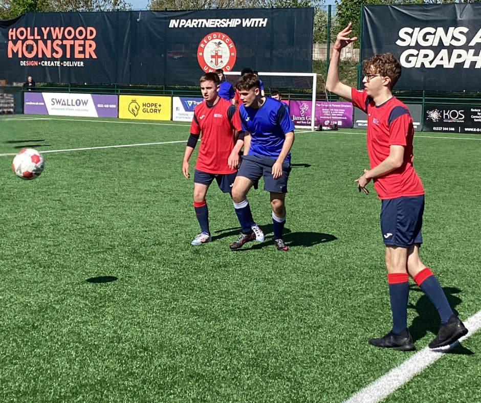 Image of QAC football team player in their red team kit on the field
