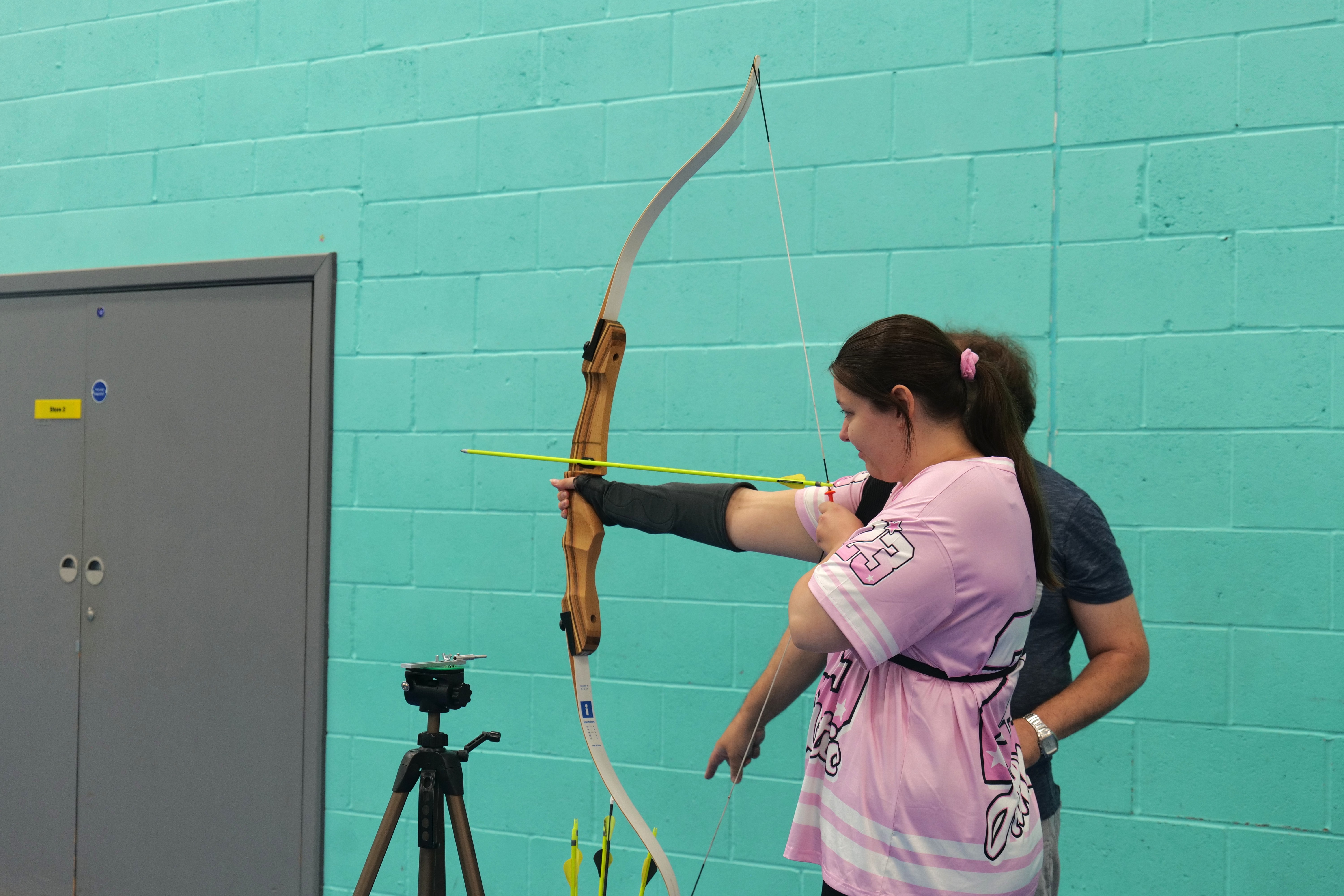 Image of a student holding a bow and arrow for archery Image of a student holding a bow and arrow for archery