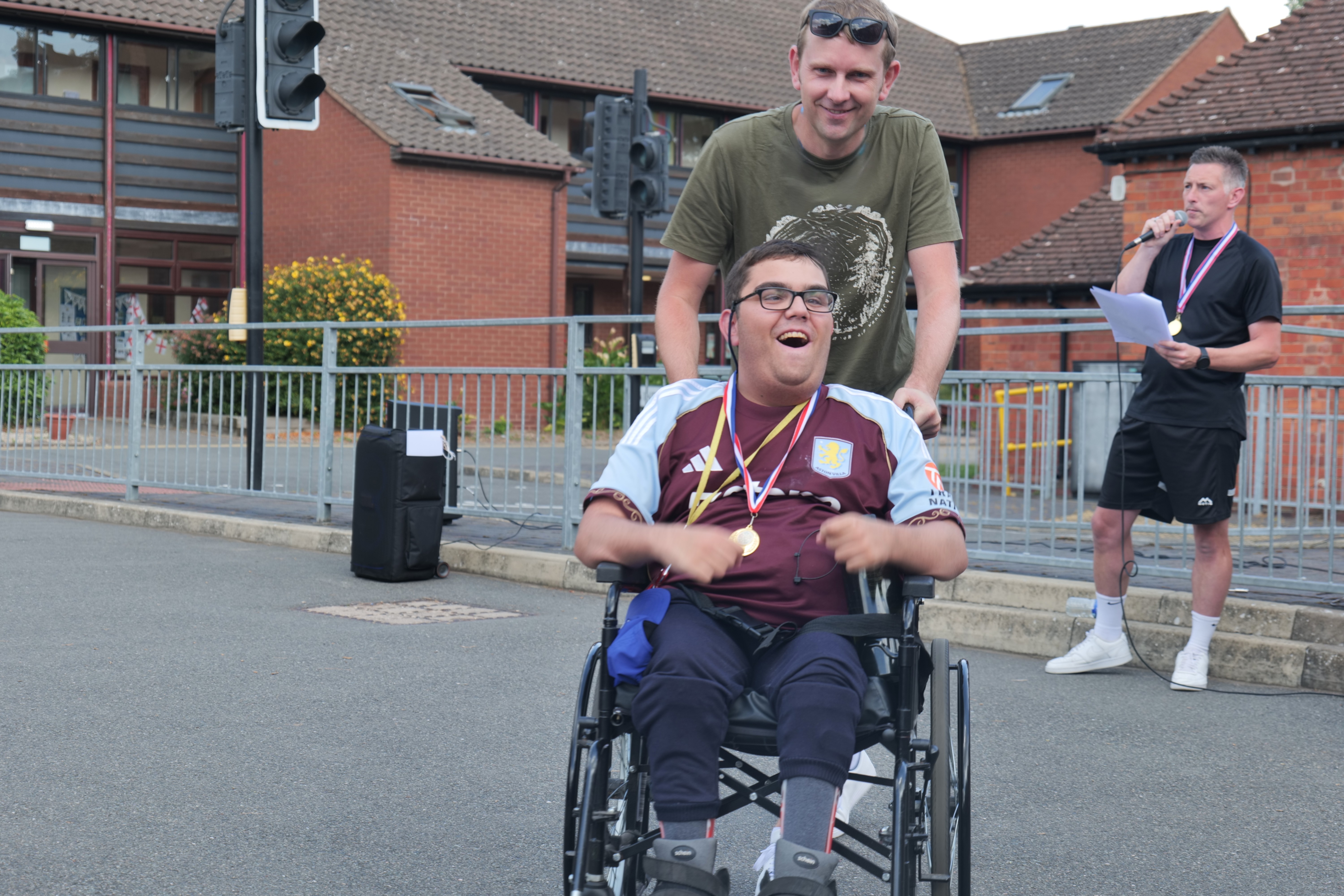 Image of a student in a wheelchair smiling wearing a medal in the courtyard Image of a student in a wheelchair smiling wearing a medal in the courtyard