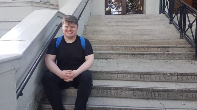 Calum sits on the steps outside the Royal Central School of Speech and Drama