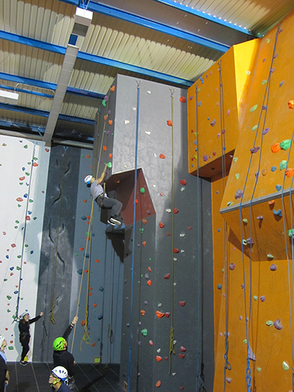 Student reaches the top of a climbing wall Student reaches the top of a climbing wall