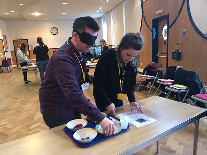 2 people involved in a blindfolded food preparation activity during the disability awareness day