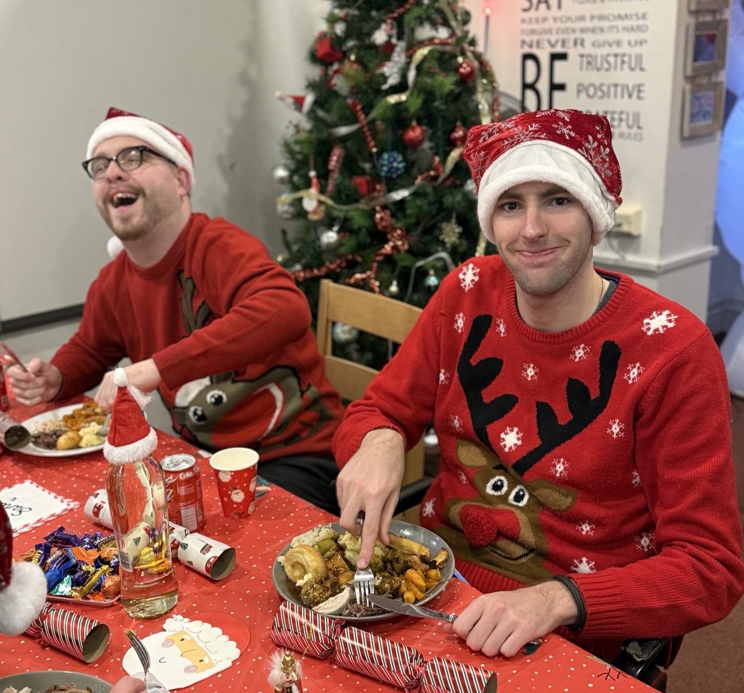 Image of two male students sat at the table laughing with a Christmas dinner Image of two male students sat at the table laughing with a Christmas dinner