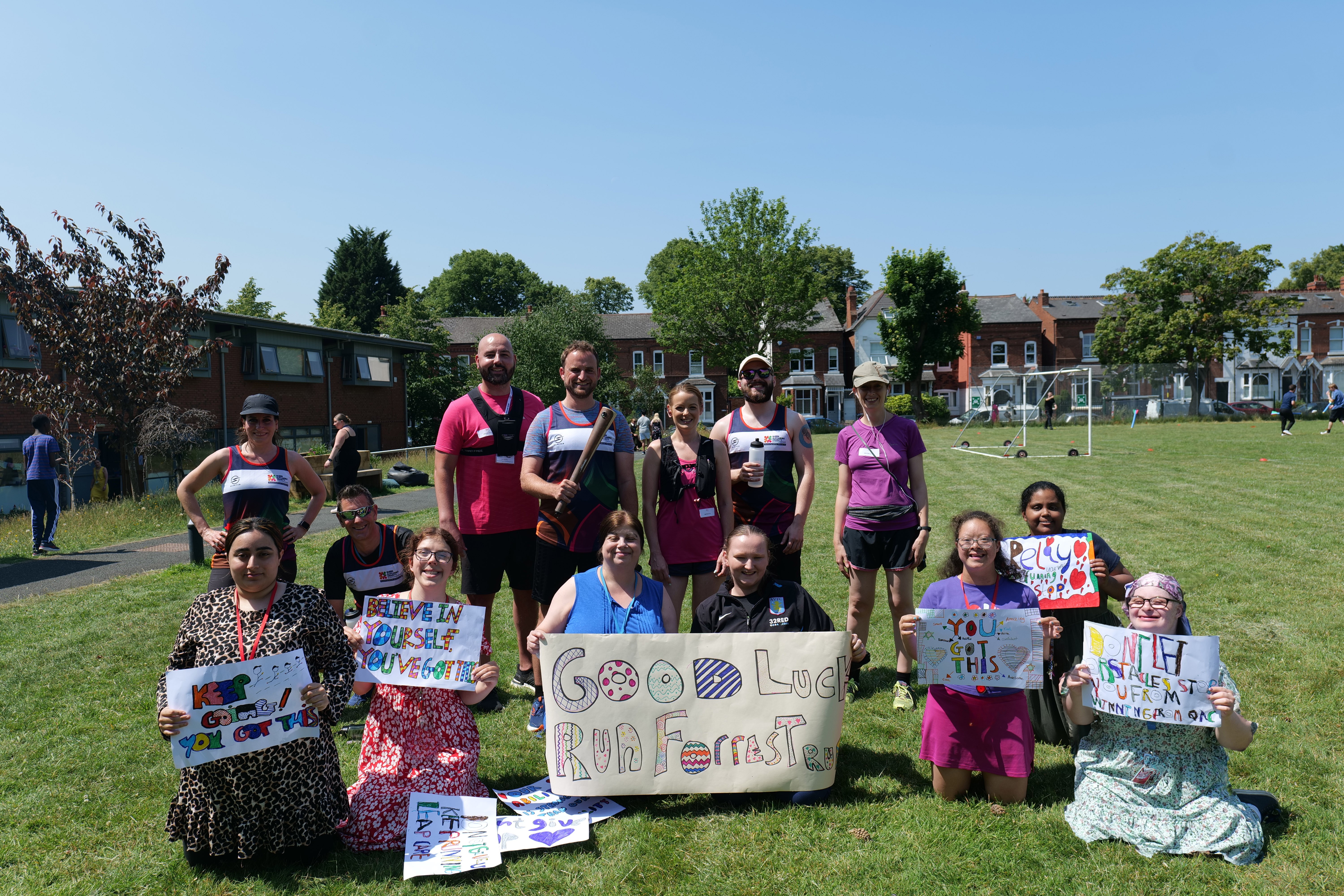 Image of QAC runners and students holding banners smiling at the camera