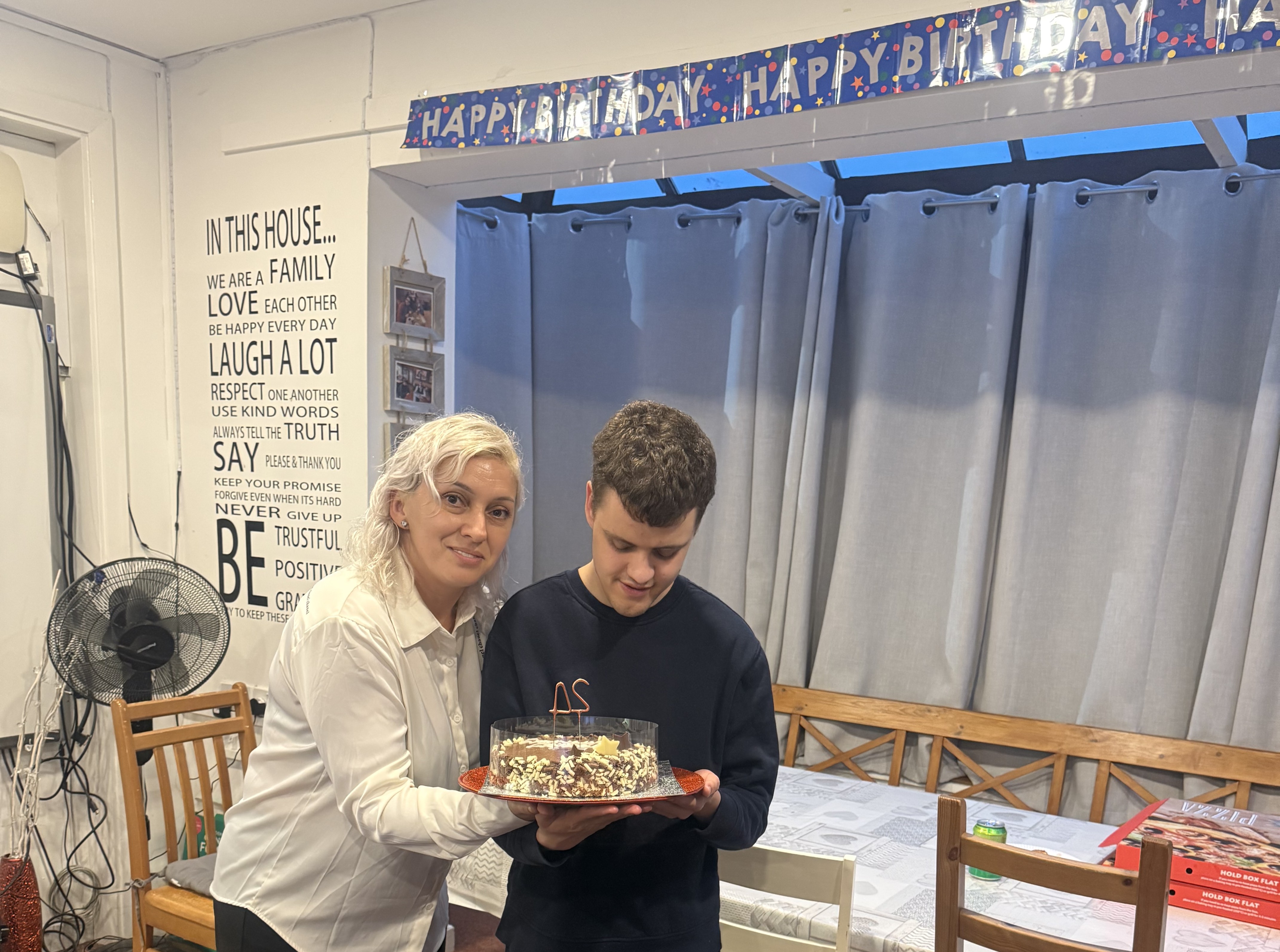 Image of Connor and house manager holding a cake smiling Image of Connor and house manager holding a cake smiling