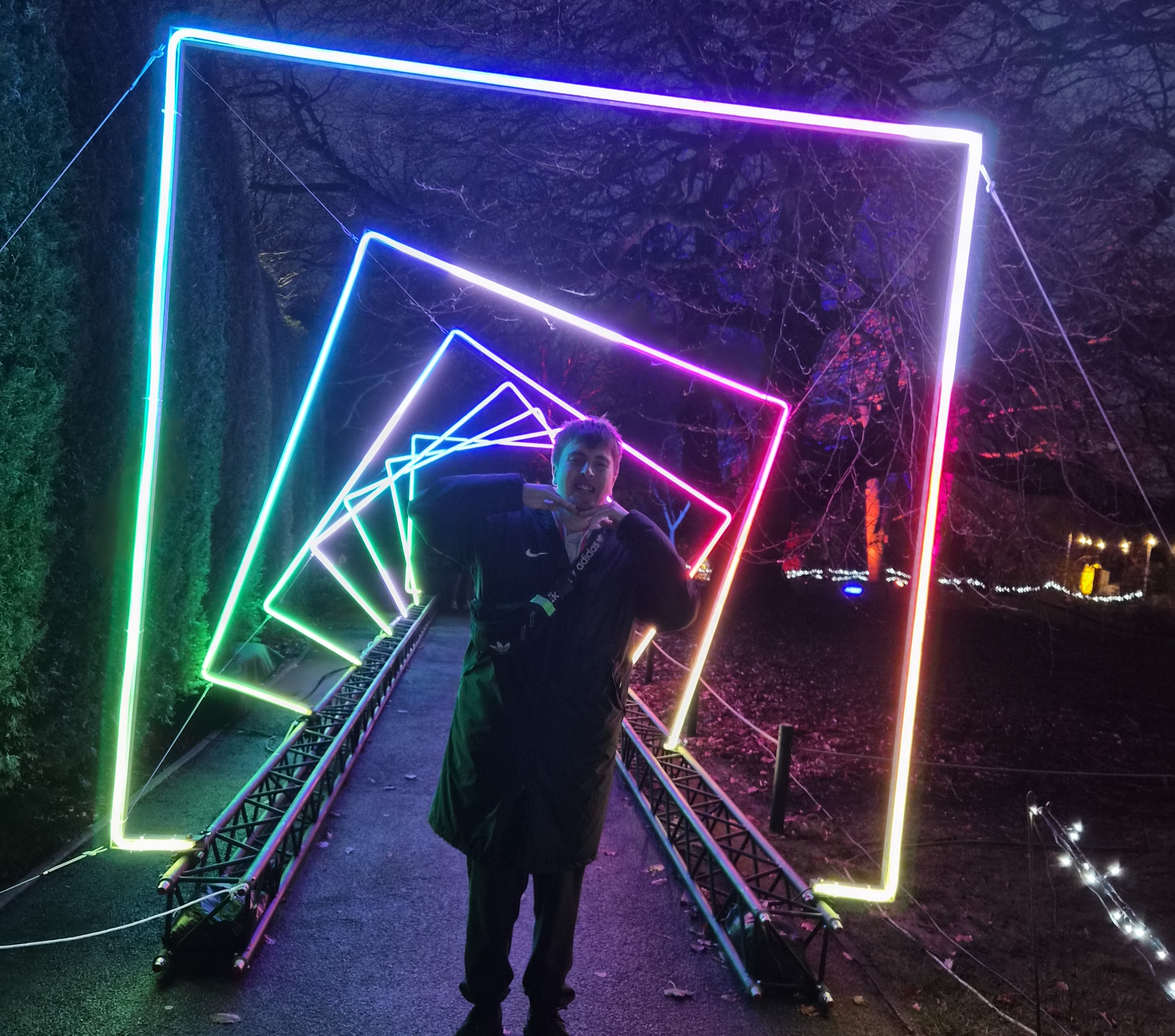 Image of a male student stood smiling with his hand flat under his chin in a light tunnel Image of a male student stood smiling with his hand flat under his chin in a light tunnel
