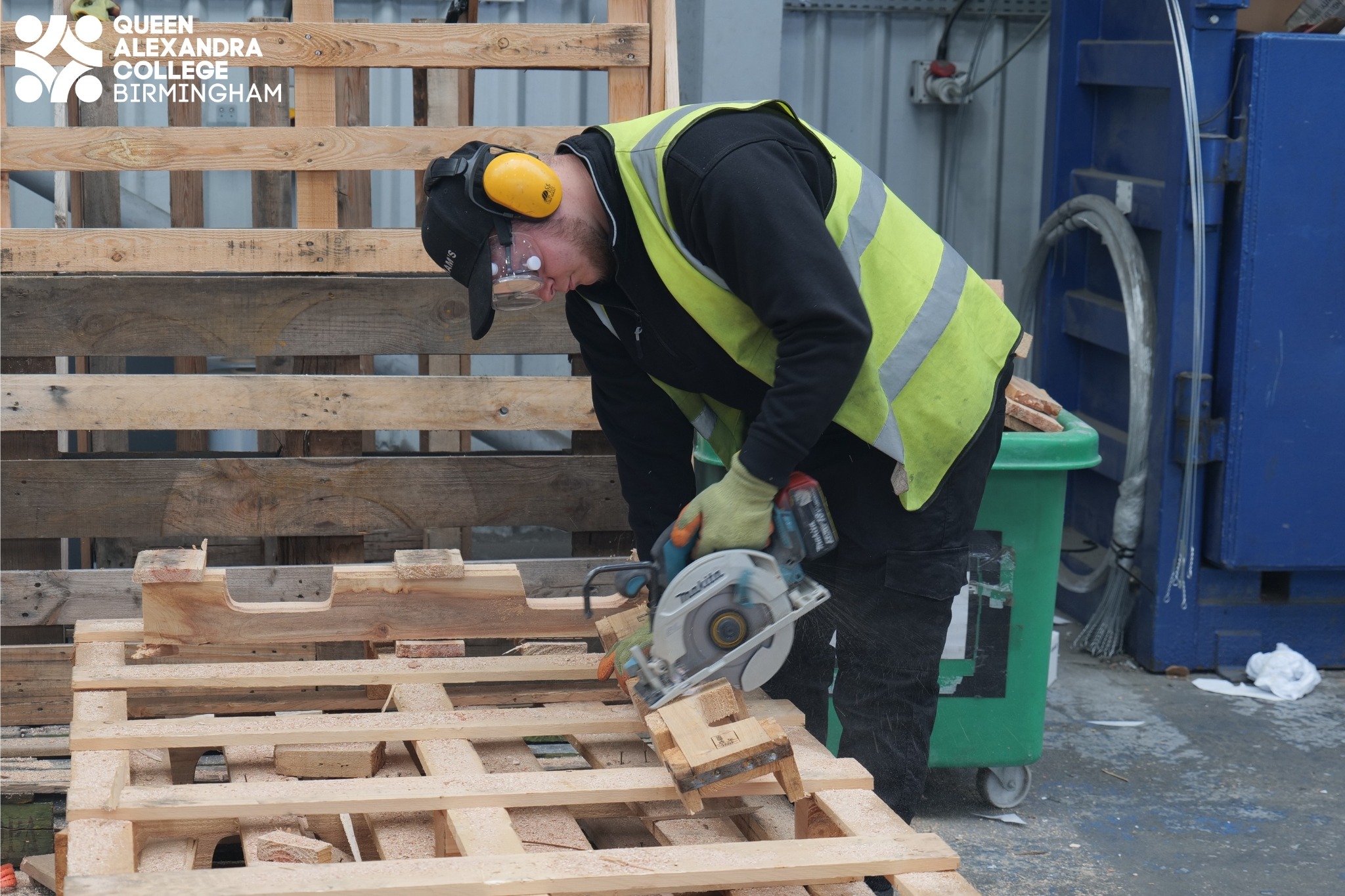 Image of Josh using a saw to cut up a wooden pallet