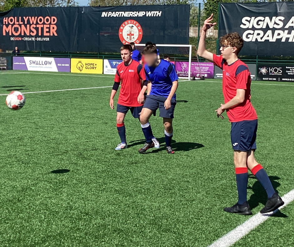 Image of QAC football team player in their red team kit on the field