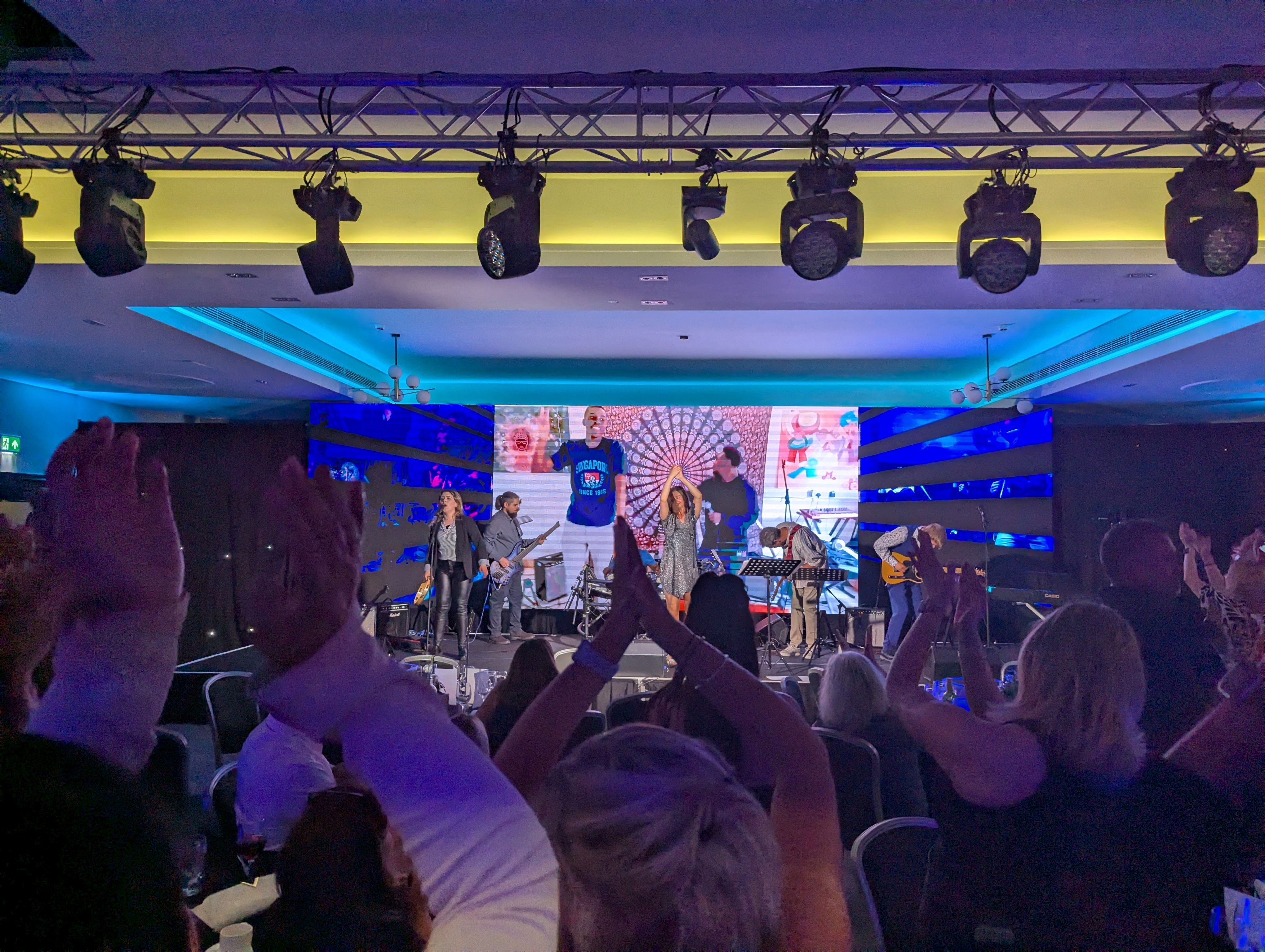 QA Collective performing on stage with guests clapping