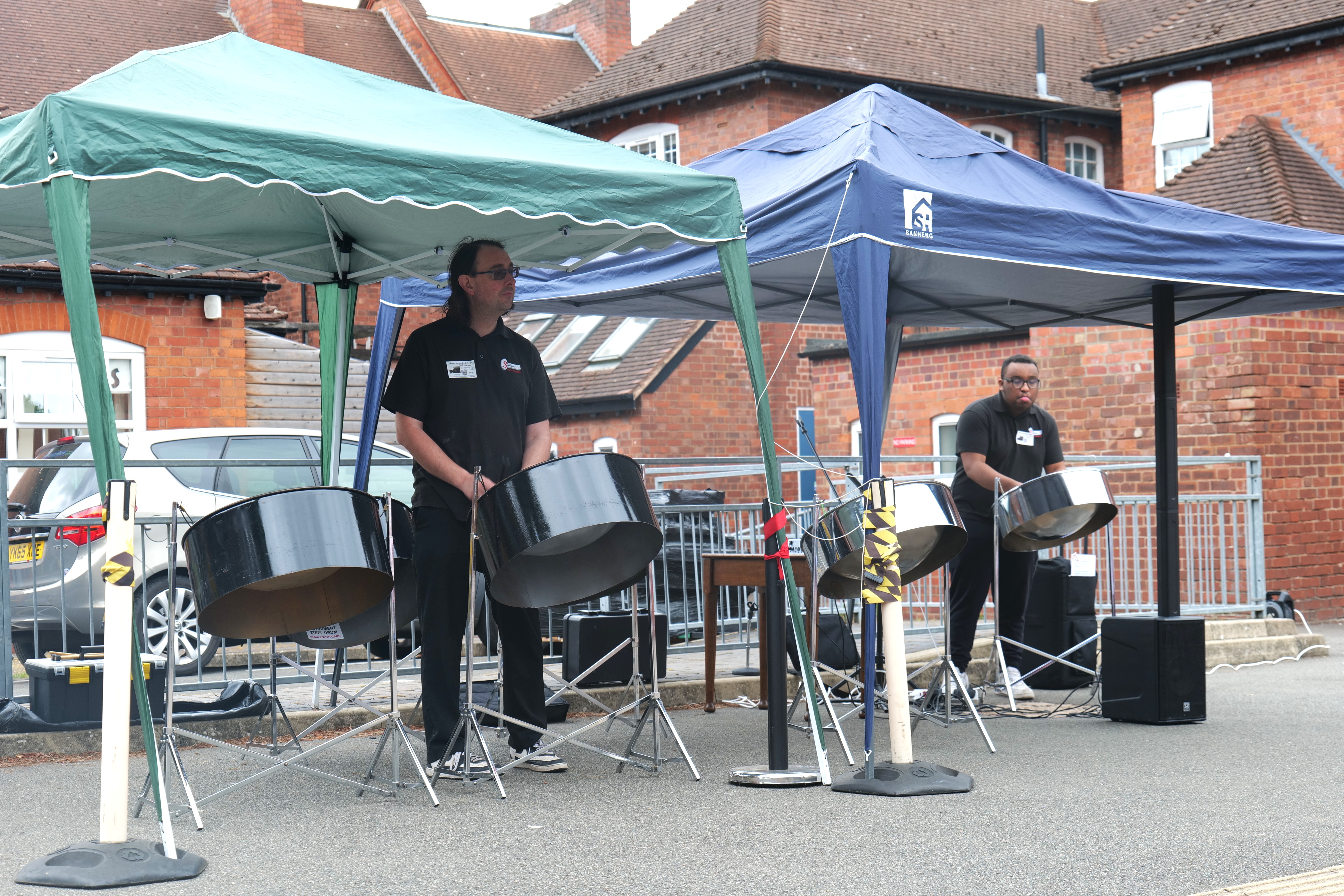Image of two people playing the steel drums in the QAC courtyard Image of two people playing the steel drums in the QAC courtyard