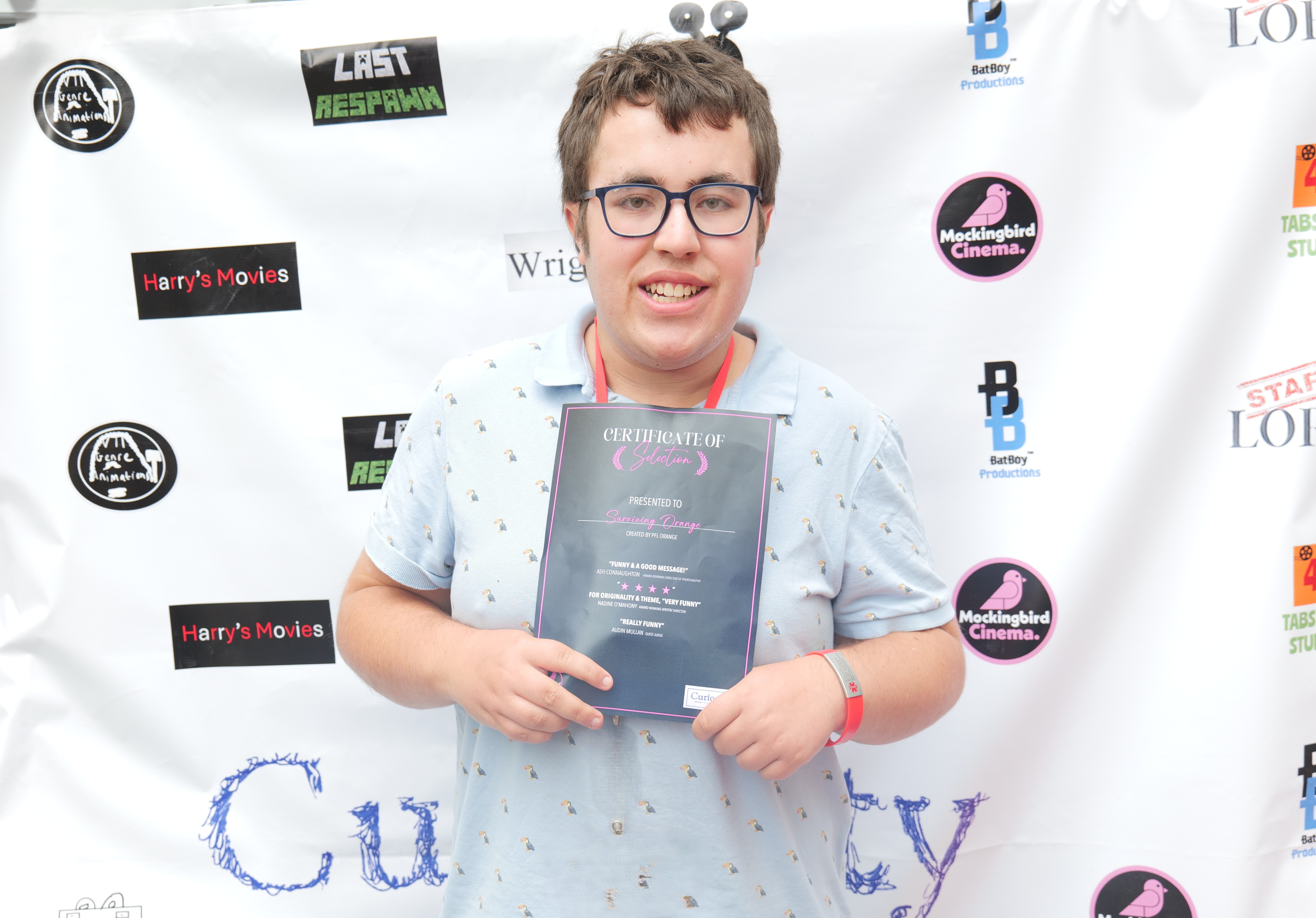 Image of a student holding a certificate smiling in front of the film festival backdrop Image of a student holding a certificate smiling in front of the film festival backdrop