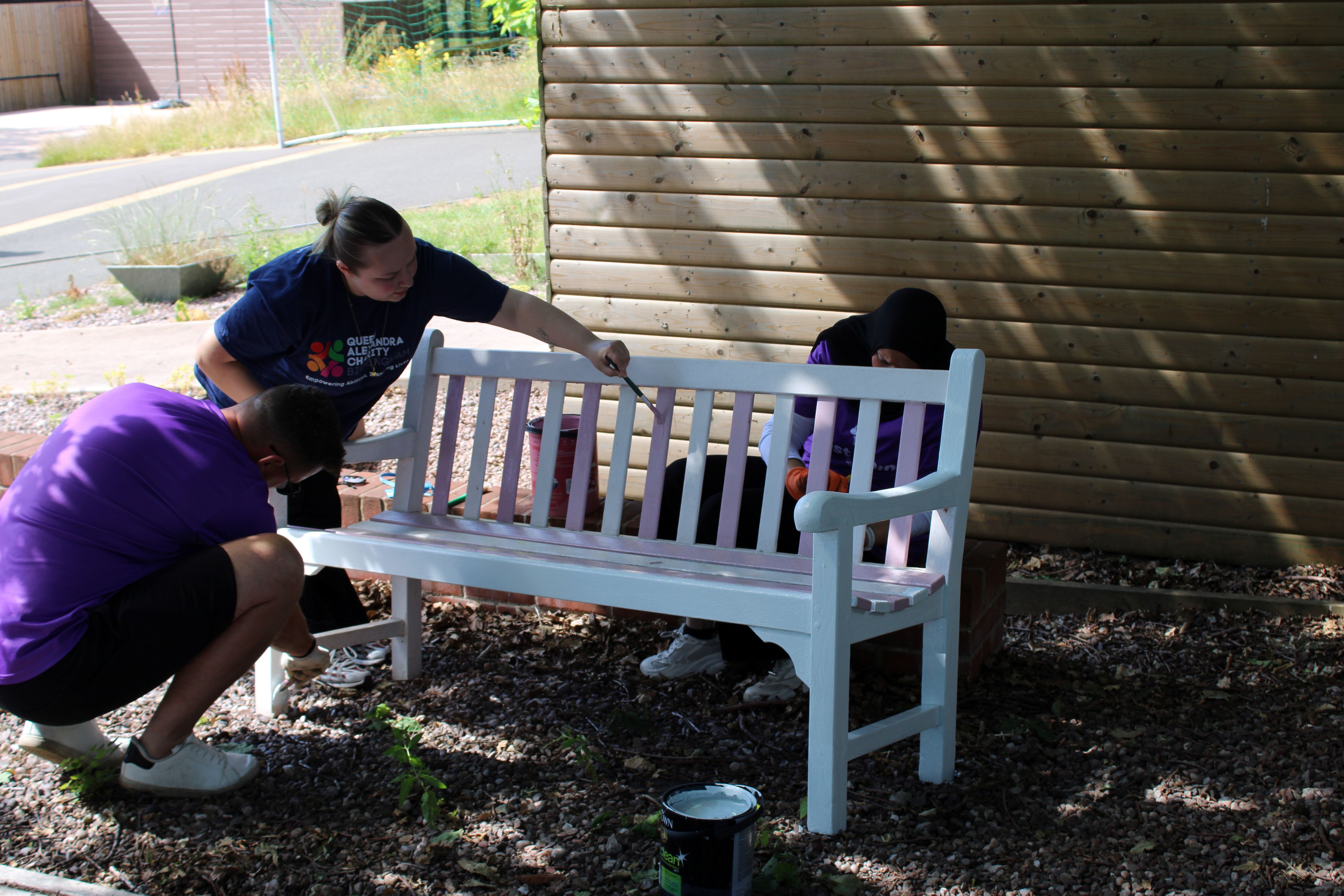 3 volunteers painting a garden bench white 3 volunteers painting a garden bench white