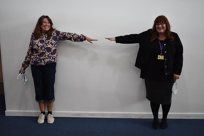 Jan and Bev pictured together with arms pointing out and almost touching fingers