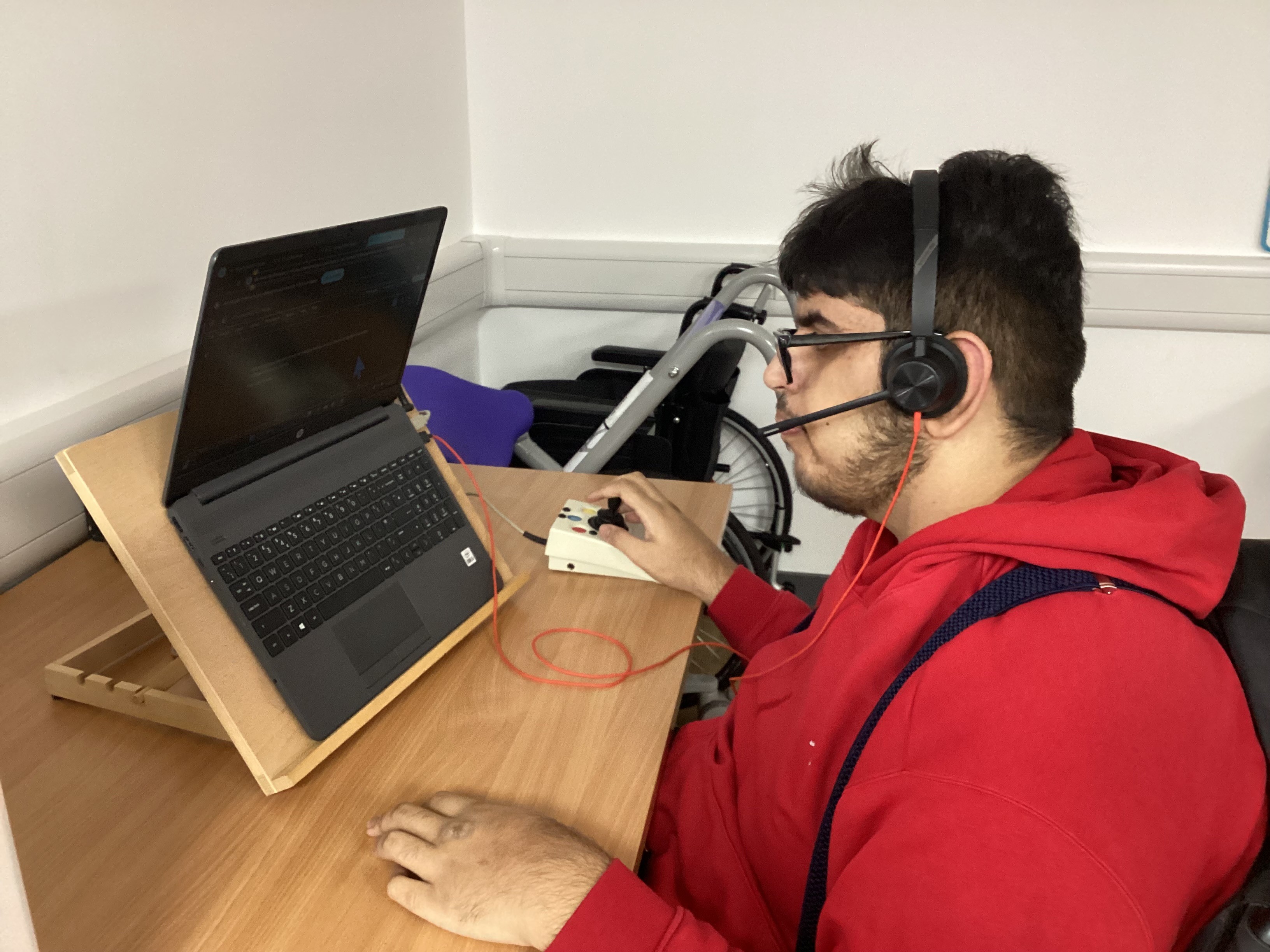 Image of Shaan using a angled laptop and assistive mouse Image of Shaan using a angled laptop and assistive mouse