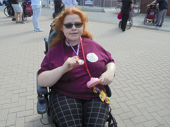 A student posing for a photo to show off her medal received during the Summer Games