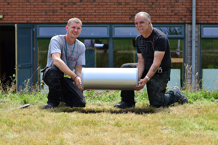 2 men laying the Time Capsule into a hole in the ground