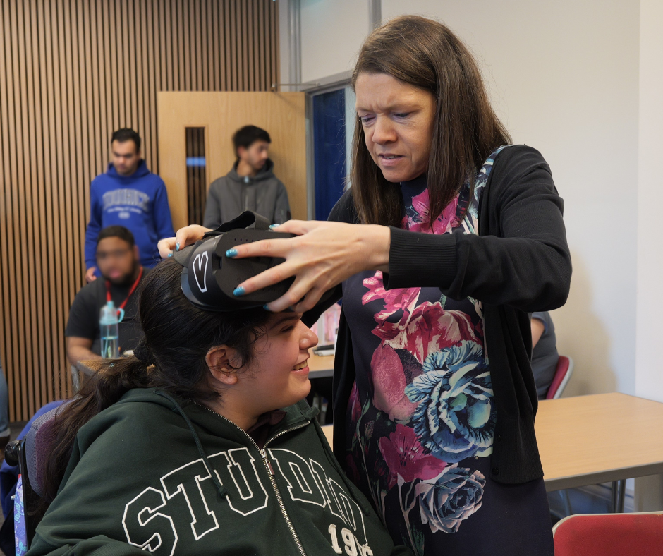 Image of QAC Staff member assisting a student to wear the Give Vision Glasses Headset /media/news/library/vg3.png