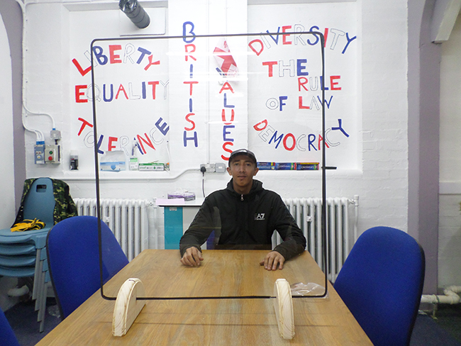 Student sits behind finished protective screen