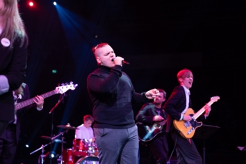 QA Collective band member sings on stage