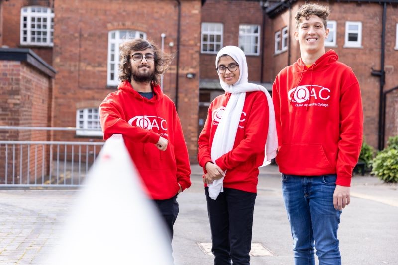 A group of QAC students wearing red College hoodies 